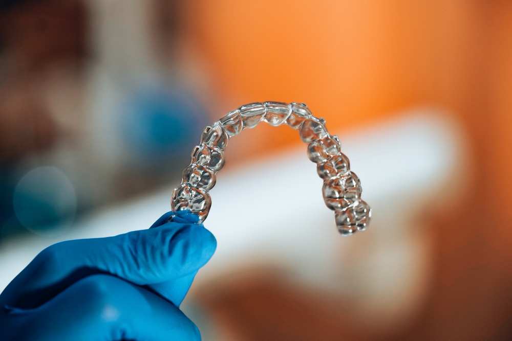 A,Dental,Nurse,With,Blue,Gloves,,Holding,An,Aligner,Which
